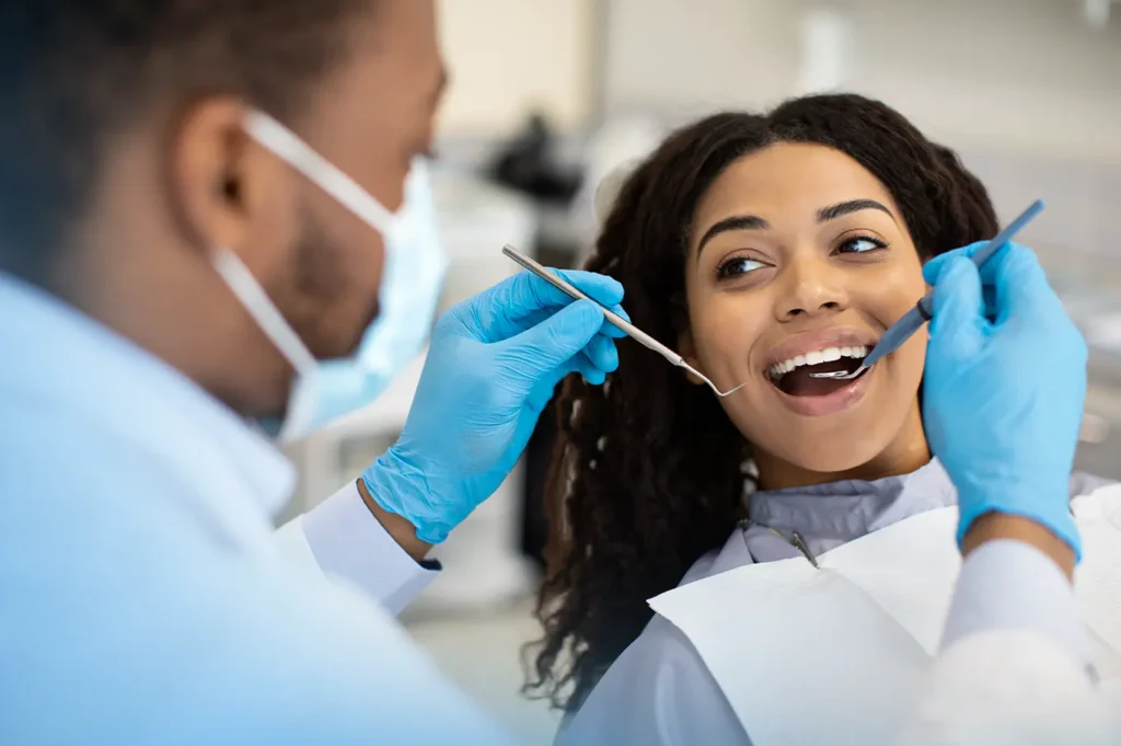 Dentist performing a patient's routine dental checkup, examining teeth with dental tools