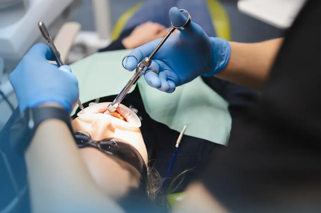 Dentist performing wisdom teeth extraction procedure on a patient using surgical tools during oral surgery in a clinical setting