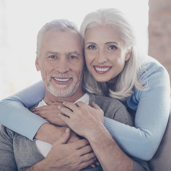 Couple smiling after saving their smiles with periodontal therapy