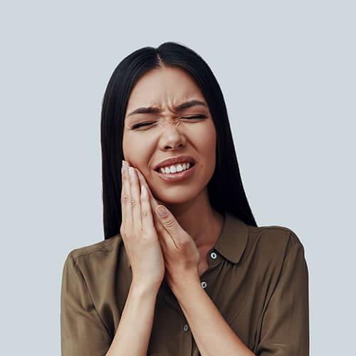 A woman holding her mouth in pain because of a dental emergency